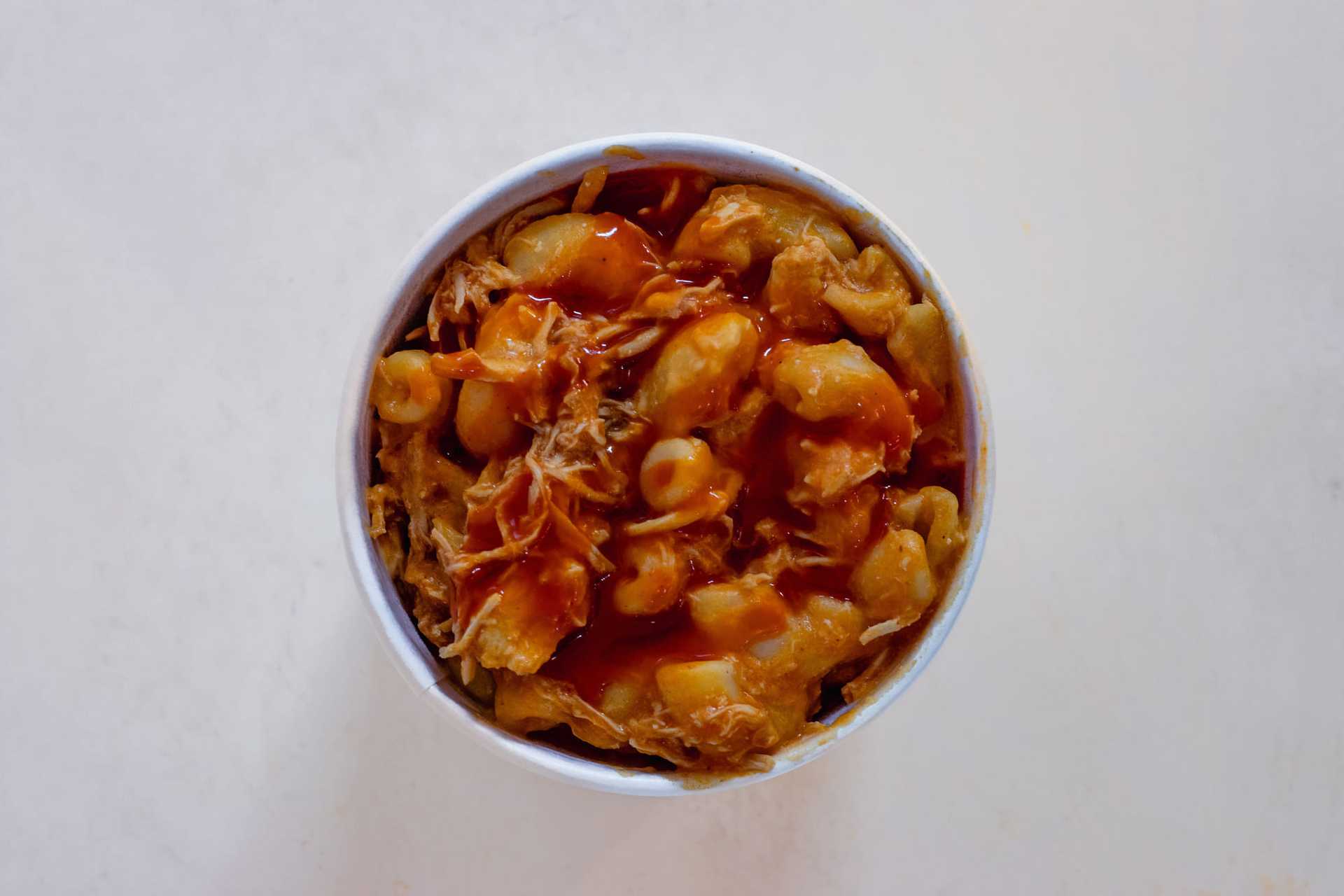 Bowl of chili with beans and shredded meat, topped with sauce.