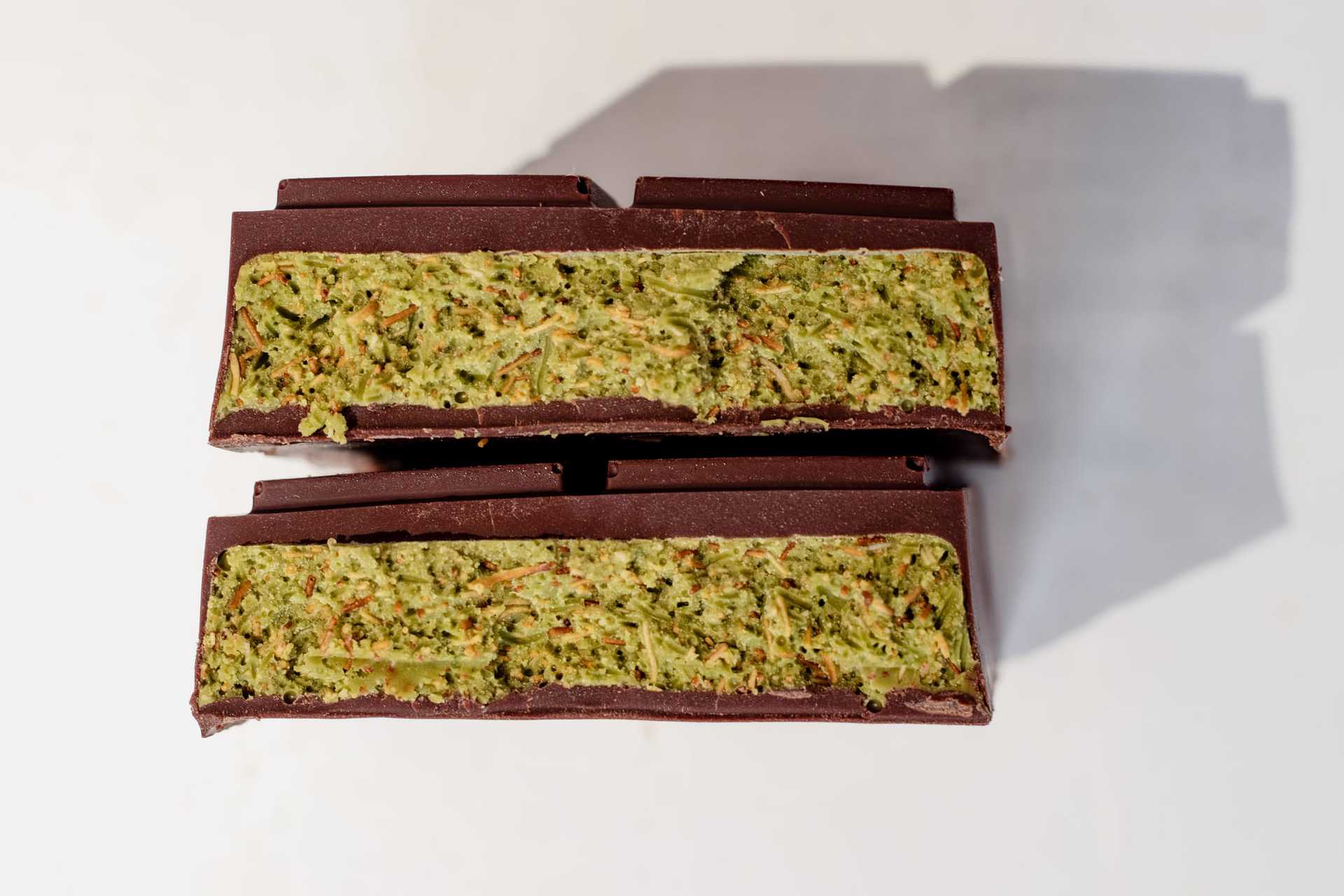 Dark chocolate bars with matcha filling, cut in half to reveal green inside.